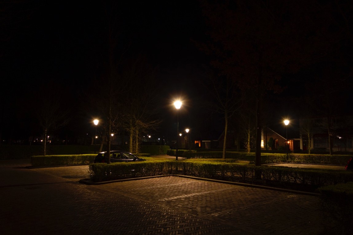 Parkeerplaatsen in het donker, met straatverlichting. Zie bijschrift onder afbeelding